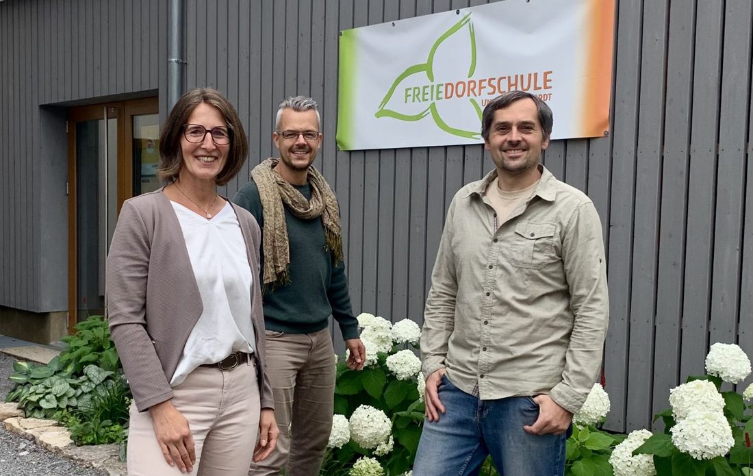 Tobias Danzer mit zwei Personen vor der Freien Dorfschule